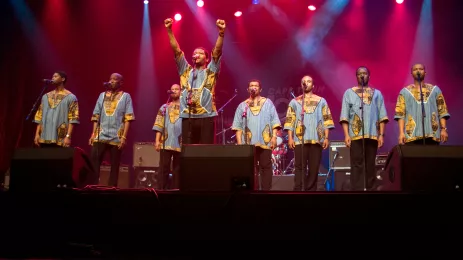 Men in blue and yellow traditional dress performing on stage