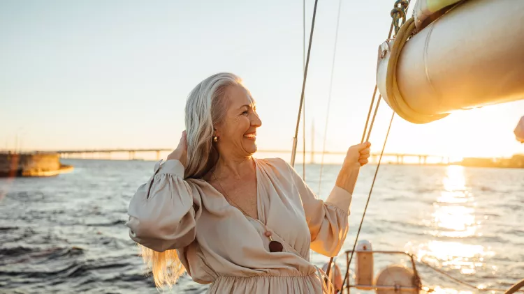 Senior woman adjusting her hair and enjoying sunset on private yacht