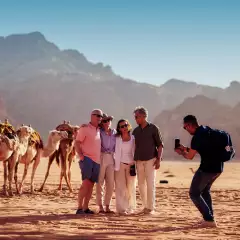 Tour group having their picture taken in the desert of jordan with camels behind