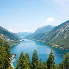 Alpine lake with fir trees and distant mountains  in Tyrol, Austria