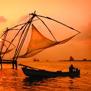 A sunset over fishing nets and boat in Cochin (Kochi), India