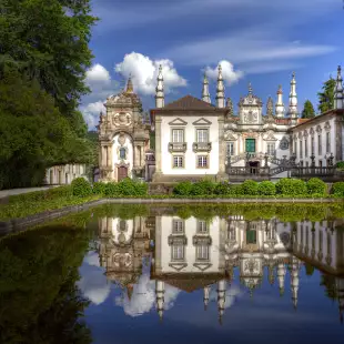 Mateus Palace by a decorative pond, it's reflection mirrored in the water, Portugal