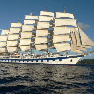 Exterior side shot of the Royal Clipper ship with tall sails cruising the ocean