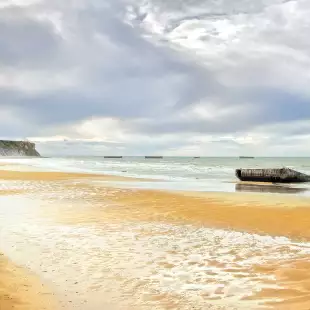 Yellow sand with glistening water on the Arromanches WWII Beach