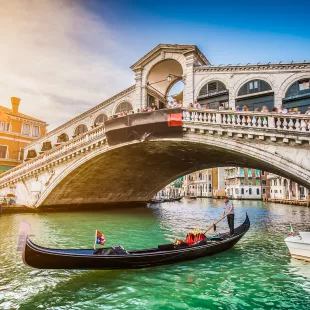 Gondola on Canal Grande with Rialto Bridge at sunset in Venice, Italy