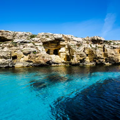 Shallow blue ocean with a background of coastal rocks 