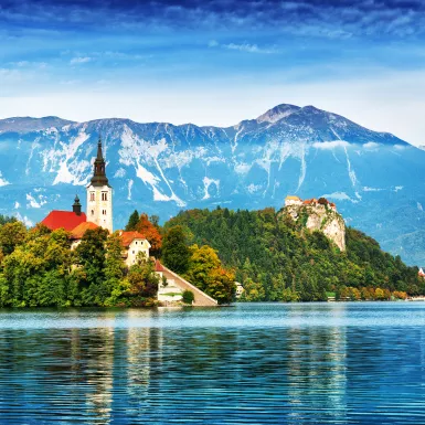 Church on the Island and ancient castle on top of a rock with European Alps in background at Lake Bled, Slovenia