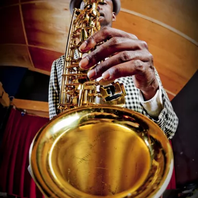 Fish-eye lens view of man playing the saxophone to the camera