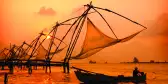 A sunset over fishing nets and boat in Cochin (Kochi), India