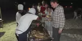 Group of people at  BBQ serving food at night