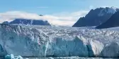 The Monacobreen Glacier with distant mountains in Svalbard, Norway