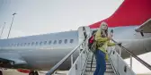 Senior woman standing on the air-stair of a plane with her boarding pass and has turned round to give one last look