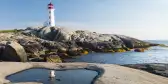 Peggys Cove Lighthouse with rocks and glistening water in Nova Scotia, Canada