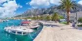 Makarska harbor under a blue cloudy sky, surrounded by the Croatia mountain range