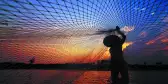 Fisherman casting a net before sunrise along the Mekong River, Thailand.