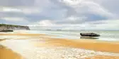 Yellow sand with glistening water on the Arromanches WWII Beach