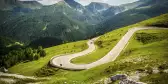 Alpina road at summer-Nockalmstrasse, curving along the natural lines of a green valley, the background showcasing nearby mountain 