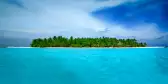 Stunningly turquoise and clear ocean waters surrounding Alimathà island with lush vegetation in the Maldives