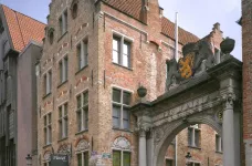 Exterior of Martin's Brugge Hotel and a nearby stone archway 