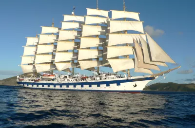 Exterior side shot of the white and blue Royal Clipper ship with tall sails cruising the ocean