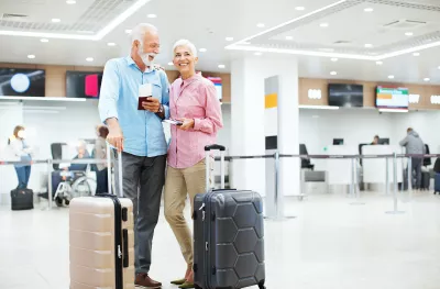 Cheerful senior couple looking at arrival departure board at an airport