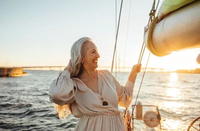 Senior woman adjusting her hair and enjoying sunset on private yacht