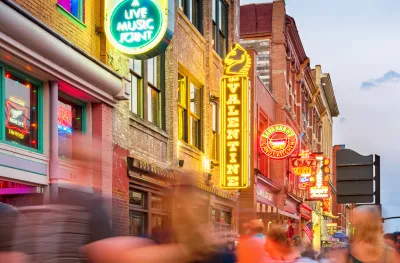 Broadway pub district with colourful neon signs in downtown Nashville, with blurred passing figures