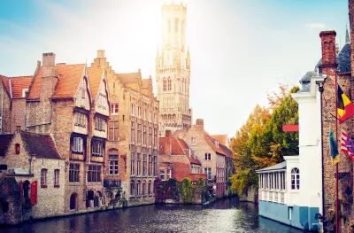 View of the waterfront buildings, canal and bell tower on a sunny day in Bruges, Belgium