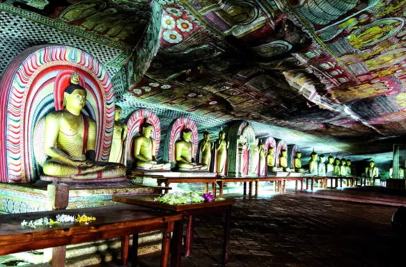 Interior of the Dambulla Golden Cave Temple with rows of golden Buddha statues and painted ceilings, Sri Lanka, South Asia.