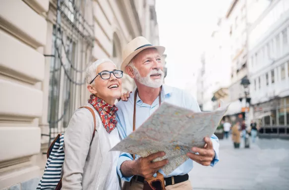 Senior couple holding a map, smiling and looking into the distance.