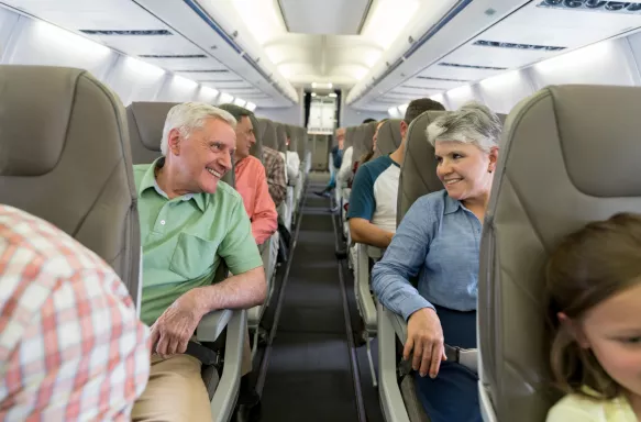 Happy senior couple on a plane sitting smiling at each other