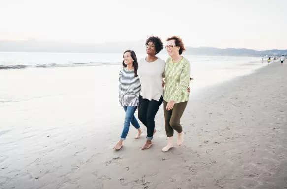 Three senior friends walking by the seashore on a bright day