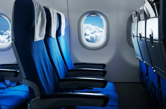 Empty air plane seats with blue sky and clouds in the window.