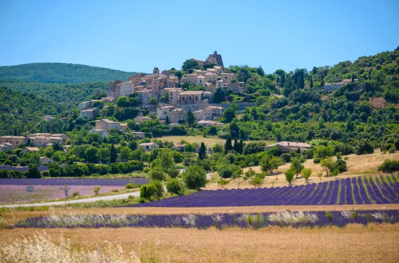 City of Saint-Saturnin-les-Apt on the hill with lavender fields in valley on summer day. Provence, France.