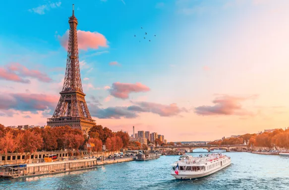 The Eiffel tower in the rays of the setting sun on the bank of the Seine river and cruise ships in Paris