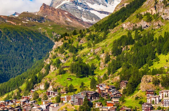 Traditional houses in Zermatt town and Matterhorn mountain with the Valais canton in the distance, Switzerland 