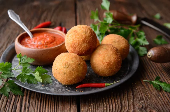 Rice balls with Arrabbiata dipping sauce on a rustic wooden background