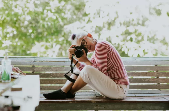 Senior Thai woman taking a professional photograph whilst sitting on a bench