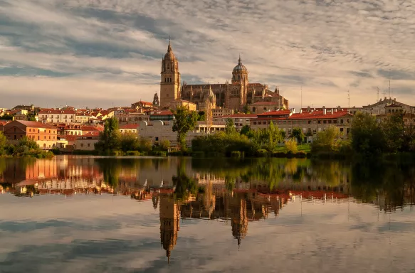 Salamanca Cathedral reflected on Tormes River during sunset in Salamanca, Spain