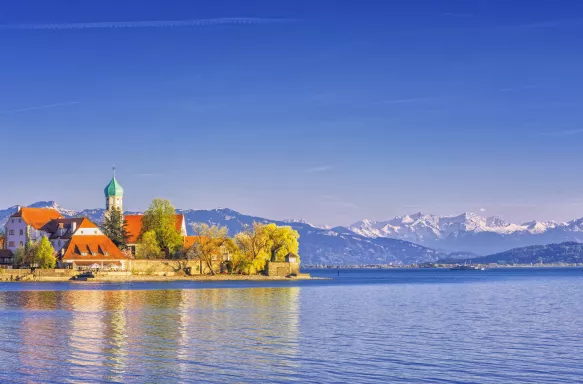 Landscape of Peninsula village at Lake Constance with the snowy Swiss Alps in the background.