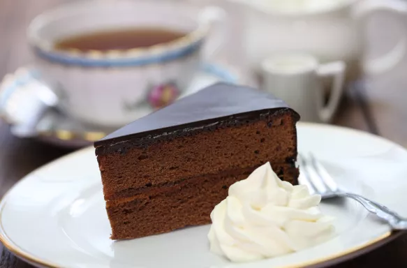 Homemade sachertorte, an Austrian chocolate cake with whipped cream and tea