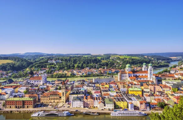 Elevated view of Passau, Germany, with sightseeing boats anchored in front of the town hall.