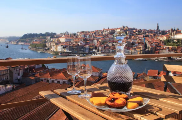 Foldable garden table with port wine and sweet treats, overlooking the Porto river in Portugal.