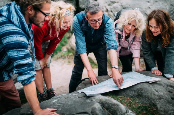 Group of Mature Hikers checking route on map in the mountains.