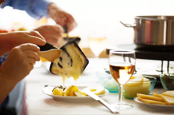 Close-up of family serving Raclette, a traditional Swiss Winter meal