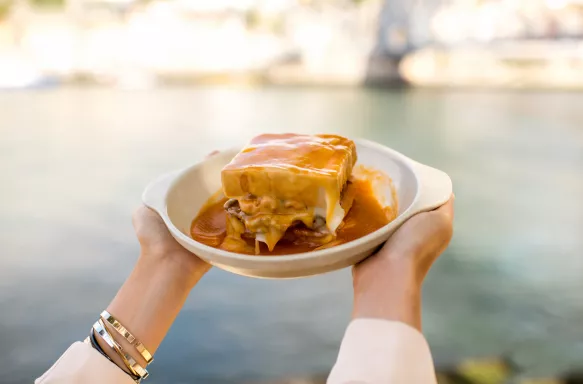 Woman holding a francesinha, traditional Portuguese sandwich in Porto City, Portugal