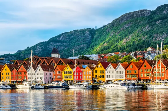 Rows of colourful buildings facing a harbour with anchored boats in Bergen, Norway.