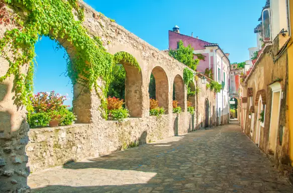 Old stone wall with arches and flowers on old European street, Ravello, Amalfi coast, Italy