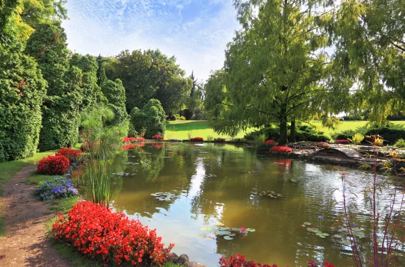 Large pond surrounded by trees and flowers at Sigurtà Garden Park, Italy.