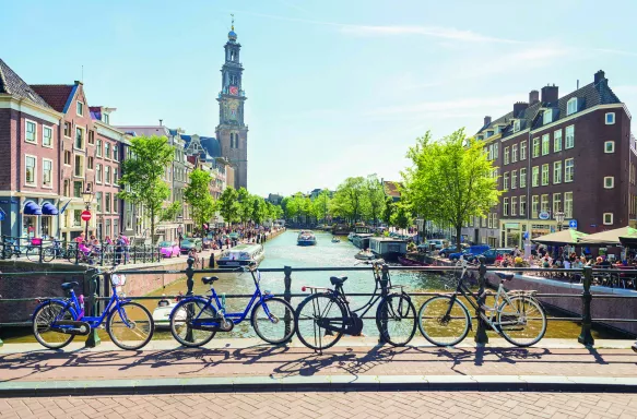 A view over a canal from a bridge with bicycles, boats and the Westerkerk in the back, Amsterdam.